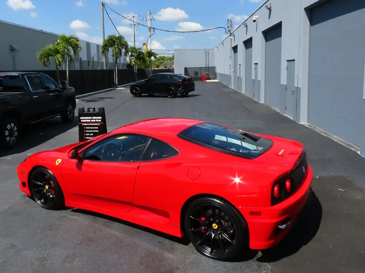 Red Ferrari 360 Modena outside the Advanced Detailing Sofla studio in Pompano Beach, beside the shop sign